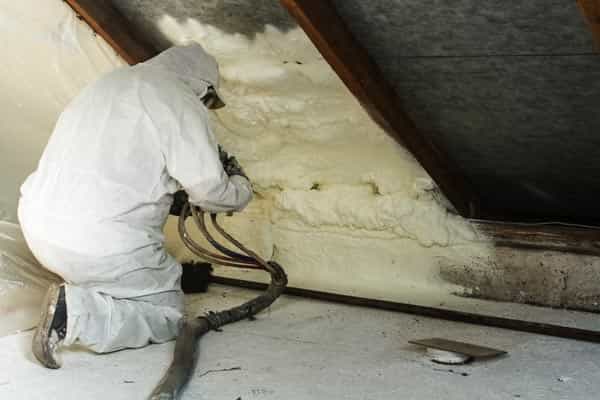 Technician applying spray foam in attic.